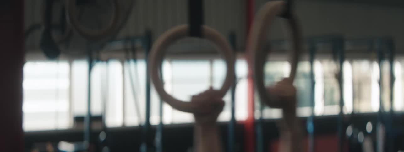 A woman grabs the rings doing gymnastics in the gym