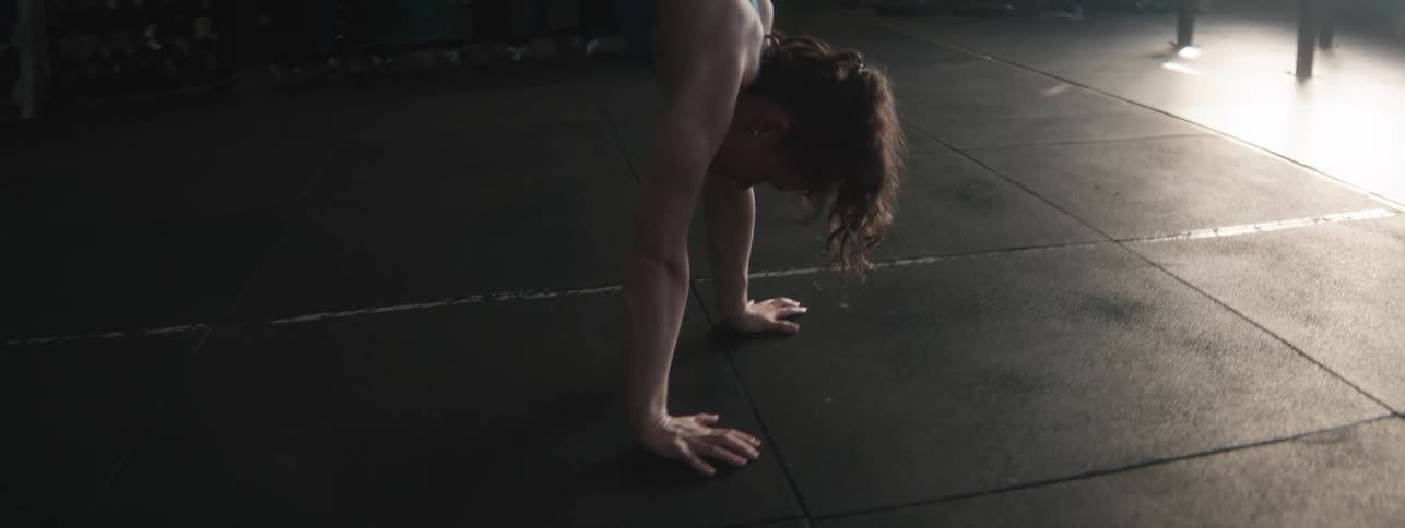 Young woman walks upside down with her hands across the gym floor