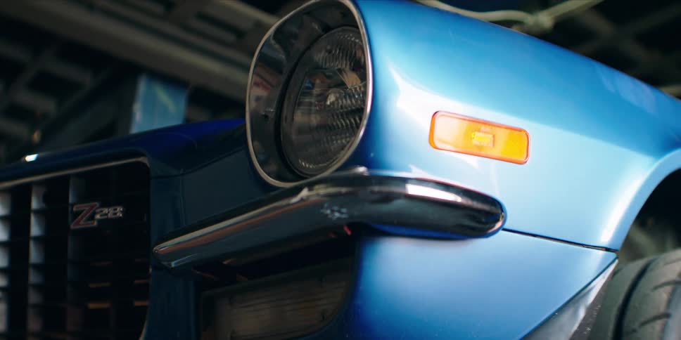 A blue 1971 chevrolet camaro z28 is parked in a parking garage at midday