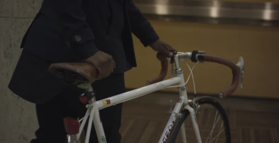 Man rolling bicycle into an elevator
