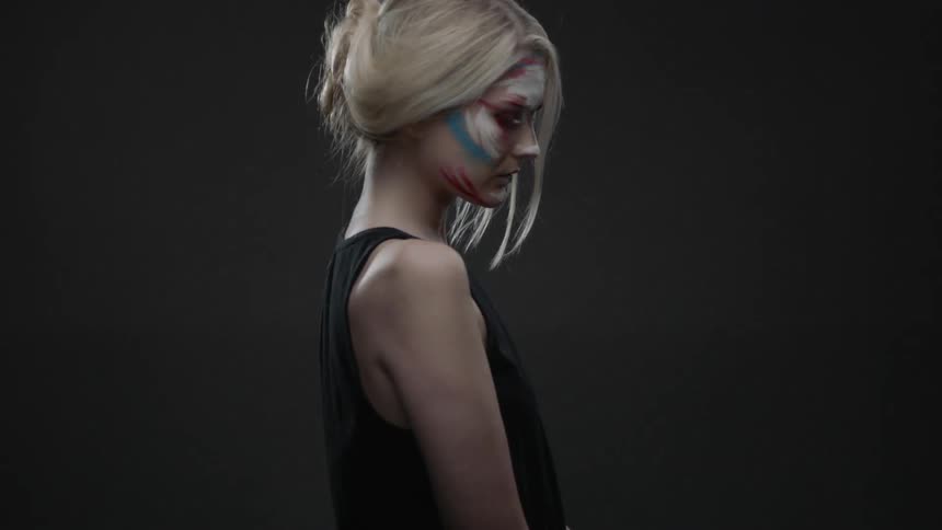 A woman with face paint turns and looks forward