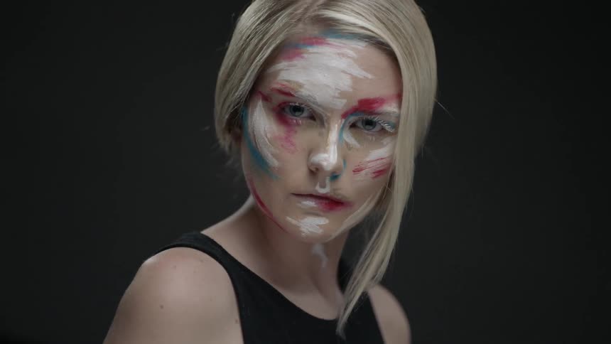 A woman wearing face paint stares outward