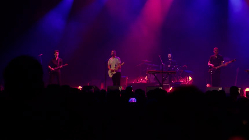 Rock band performs for a large crowd at a concert venue