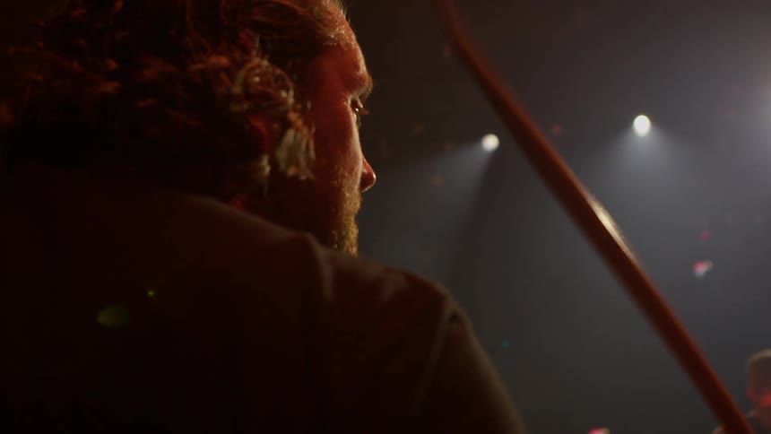 A man is playing drums on the dark stage