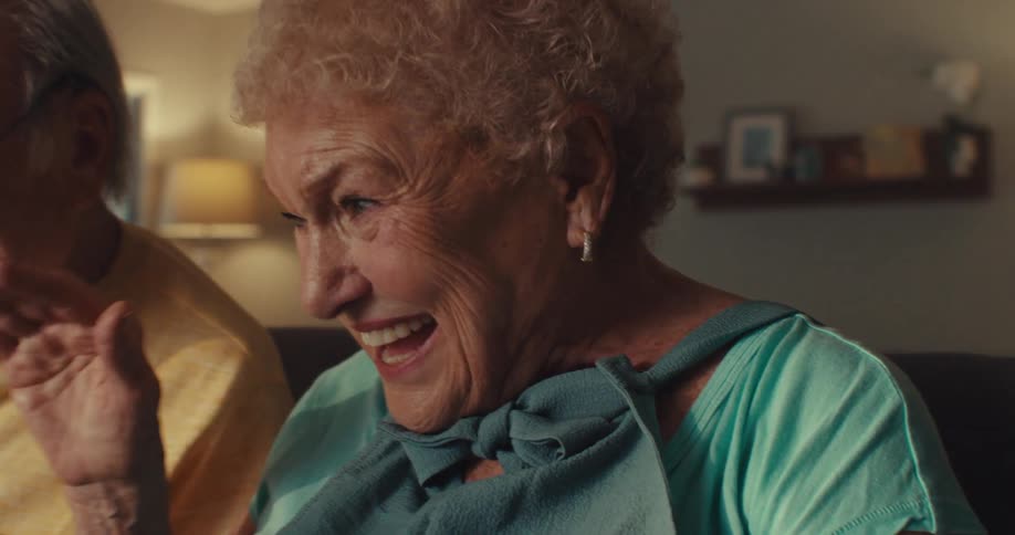 Elderly couple sitting at the table happily and interacting with a tablet in front of them