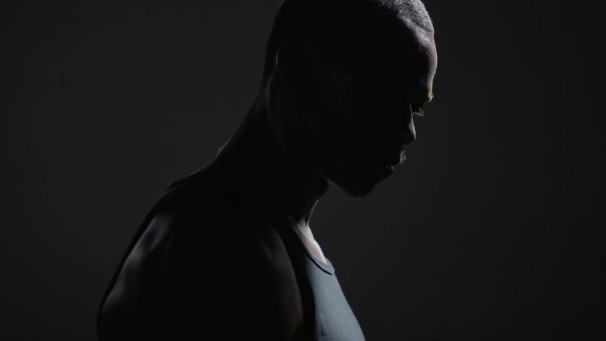 A man stands in a dark room and turns his head