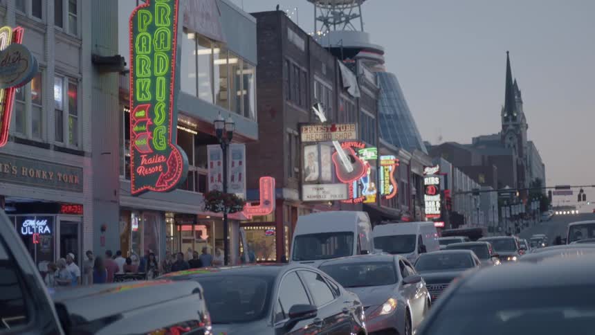 People walk along a neon light lined sidewalk