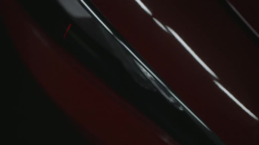 Light reflects off the hood of a red car