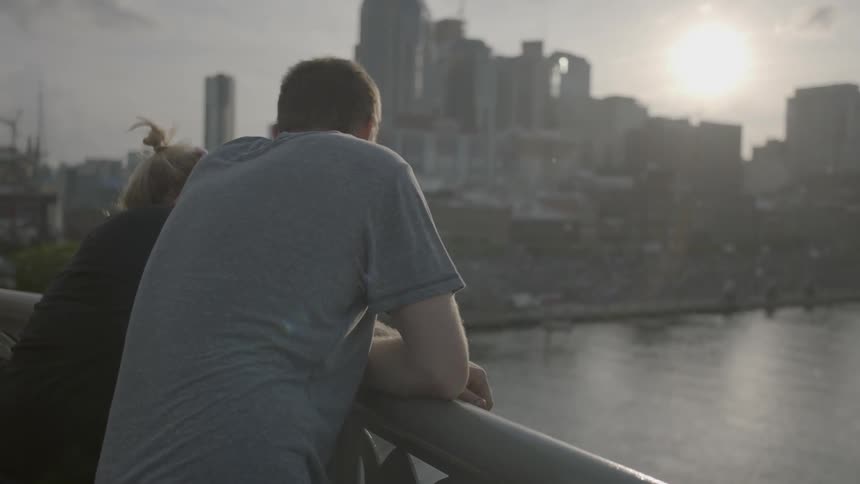 A man and women look over the railing towards a city