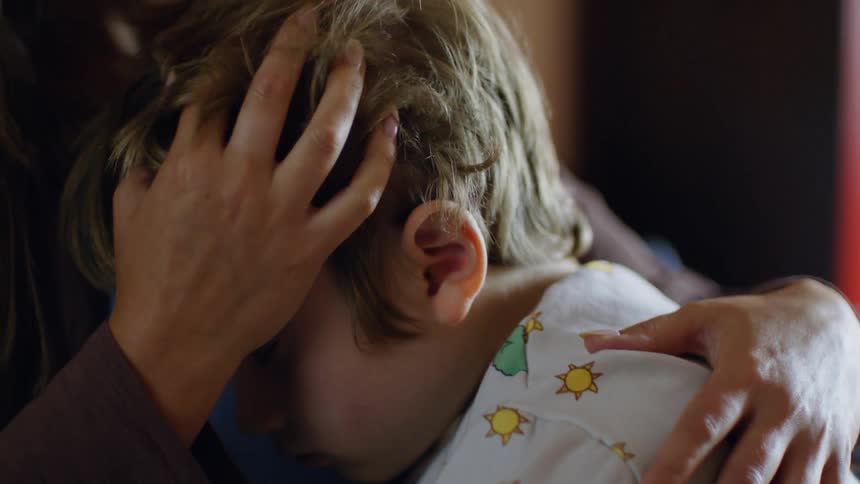 A mother is hugging her son