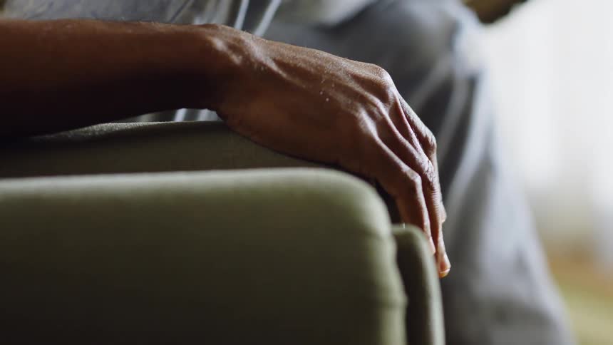 A man taps his finger son the couch arm