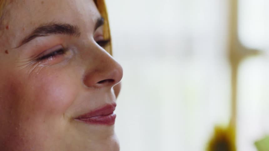 A hand gently touches the side of a persons head in a closeup interaction
