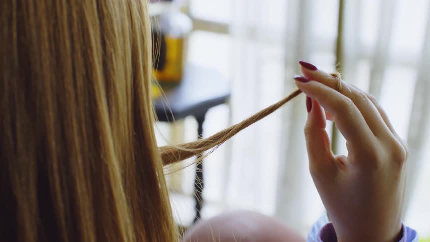 A woman is twirling her hair while she sits