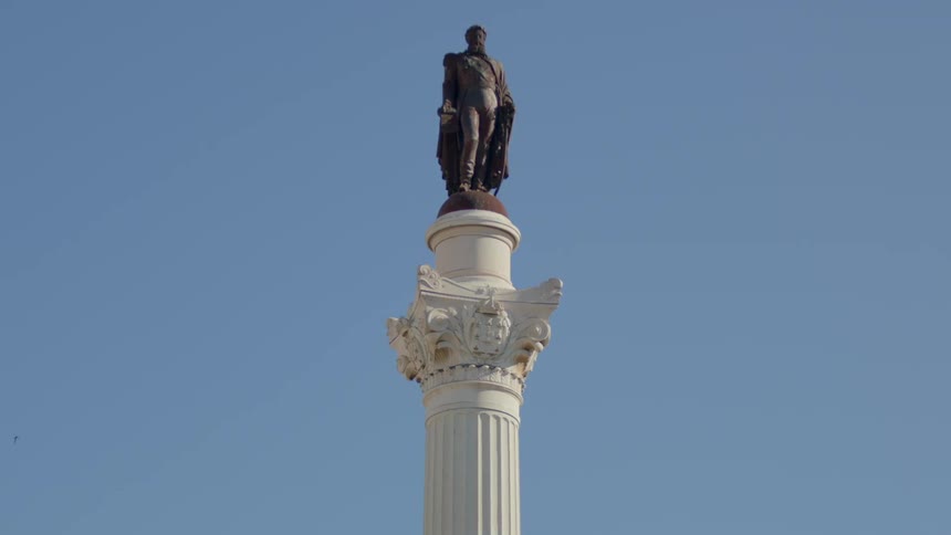 A statue stands atop a tall pillar