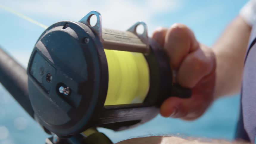 Pair of hands handling a fishing reel and rod