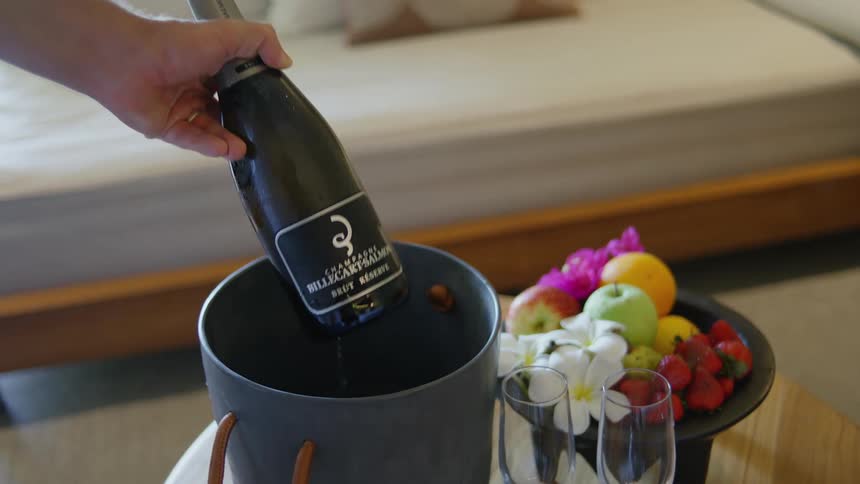 Pulling out champagne bottle from ice bucket in a hotel room
