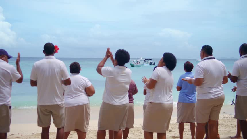 Group standing on the beach claps while singing on a summer day