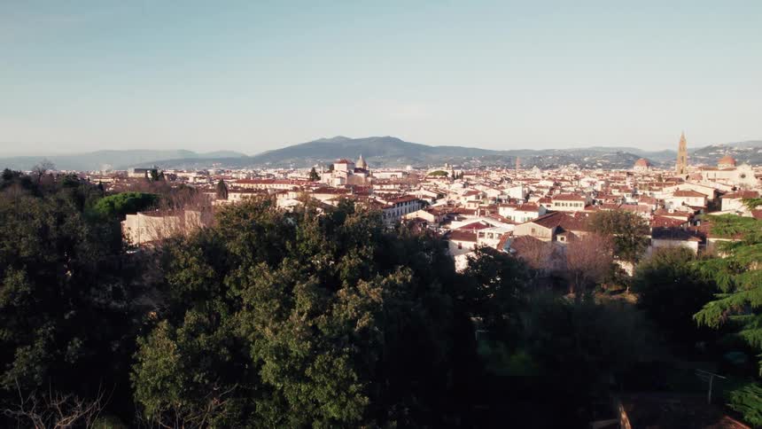 Aerial view of a european city with redroofed buildings surrounded by hills under clear sky