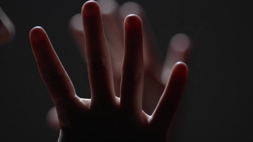 Woman brings her hands down in a dark room