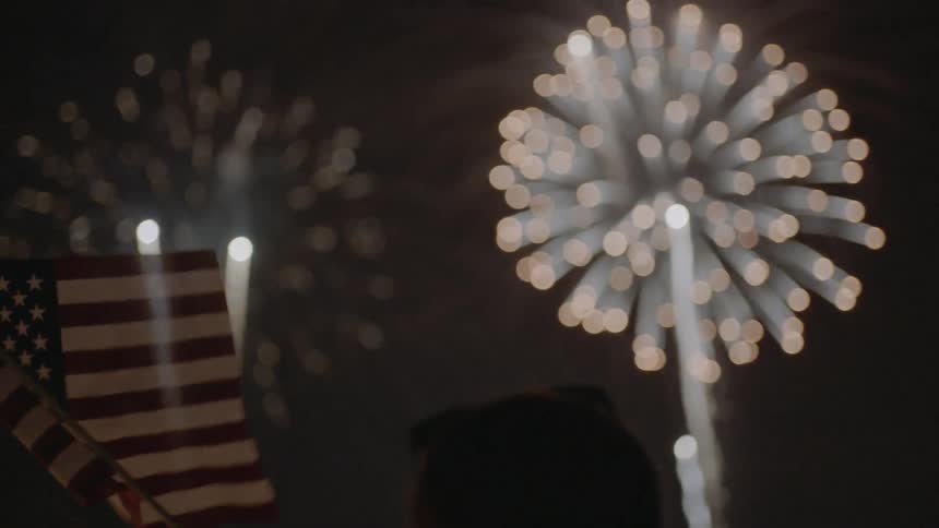 Woman waves a flag while fireworks explode