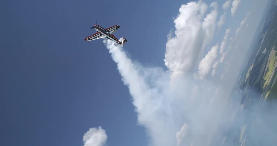 A stunt plane soars vertically into the sky trailing thick white smoke behind it
