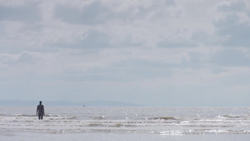 Statue of standing person in shallow ocean water