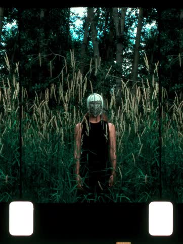 Young woman models a mask while standing in between tall grasses outdoors during daytime