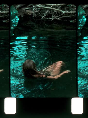 A teenage girl in a swimsuit swims underwater in a clear greenishblue river surrounded by tree roots and branches