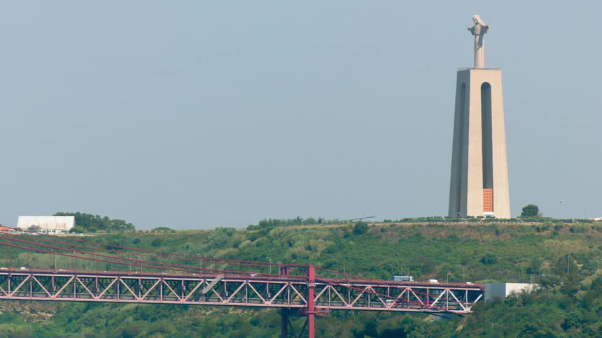 Cars travel on a bridge near a giant statue of jesus
