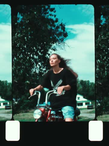 Young woman rides a motorcycle in a city street during daytime