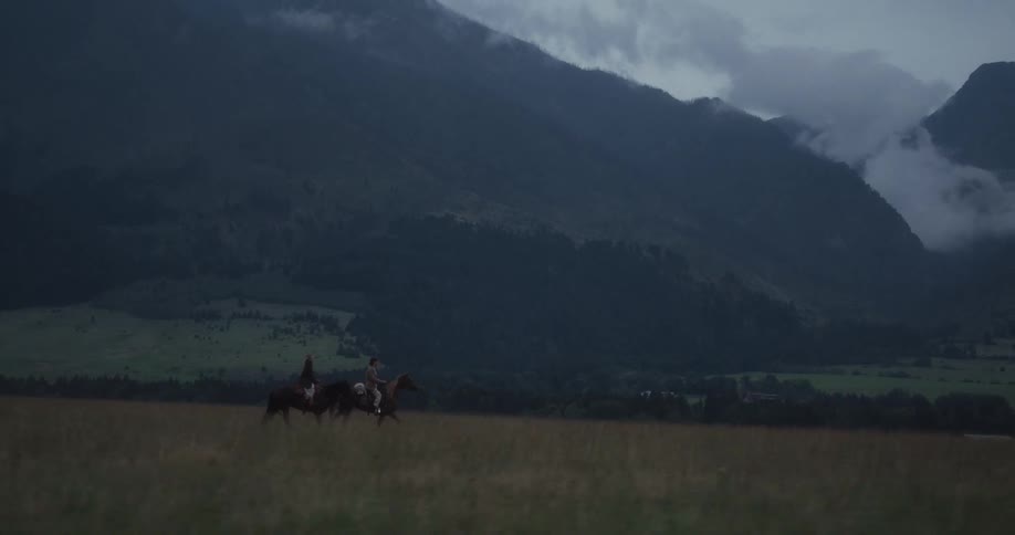 Two people horse back riding in a rural area together