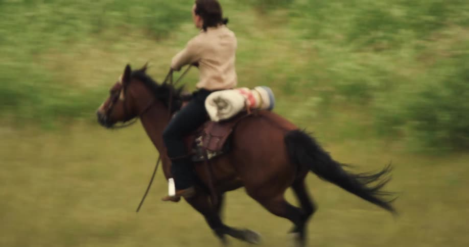 Man speeding on a horse through a field