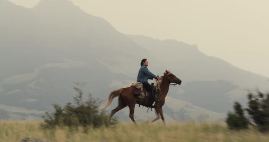 Man and woman riding horses through the mountains