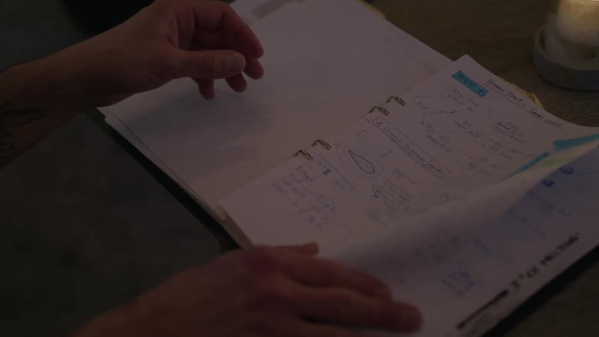 Man flips through a binder looking for a particular sketch