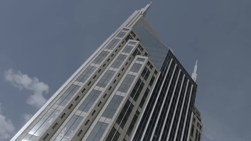 A puff of clouds move behind a tall modern building