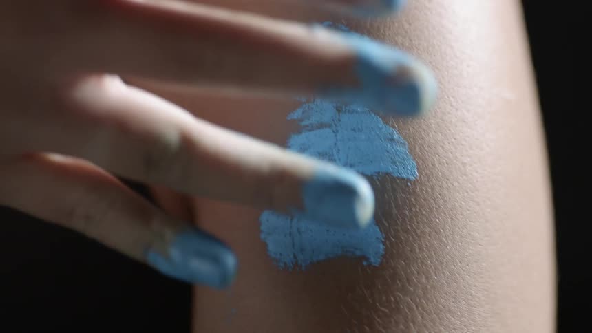 Person dabs blue paint on their arm