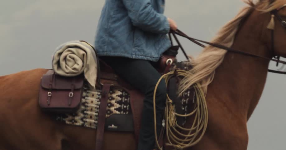 Man and woman ride horses while the fog obscures the mountains in the background