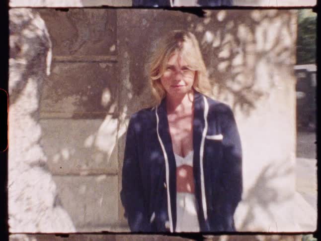 Woman in blue blazer leaning against a wall on an urban sidewalk