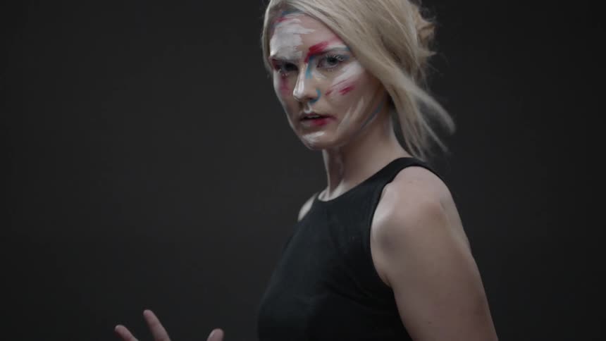 Painted blond woman lowers her hands