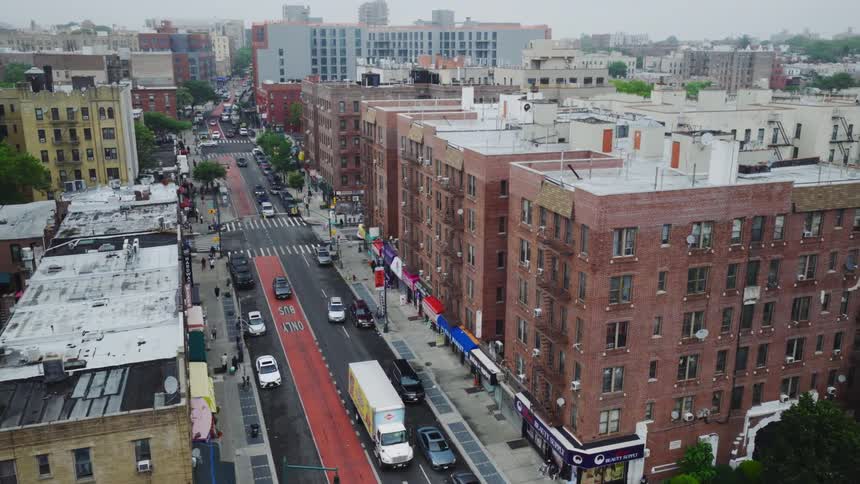 Aerial view of light traffic on a downtown city street lined with tall brick buildings on a cloudy day