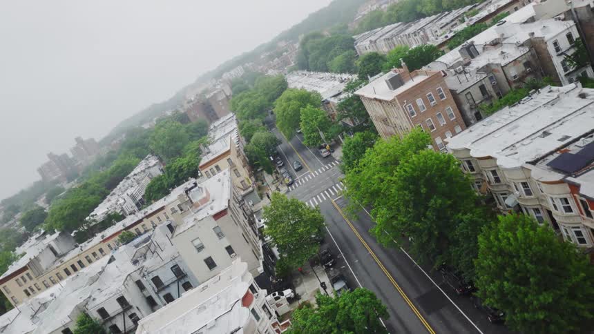 Pedestrian and vehicles cross at an intersection in a residential neighborhood on a foggy summer day