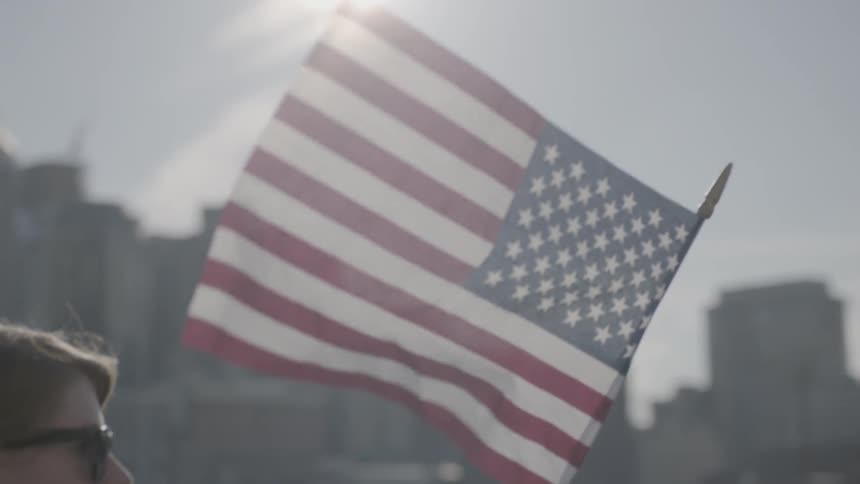 A boy in sunglasses holds an american flag