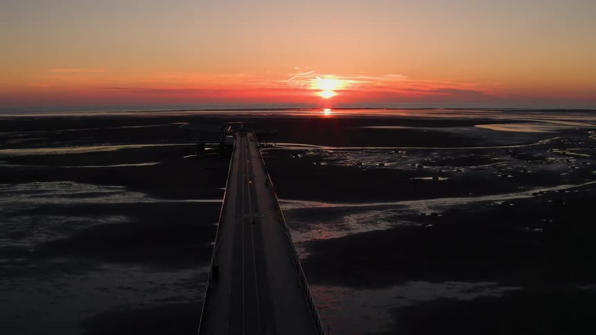 The sun setting over a long bridge expanse