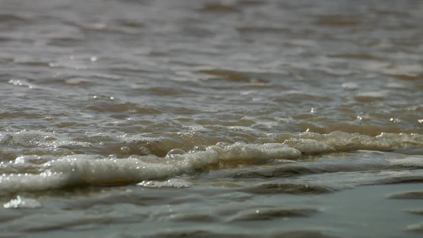 Small foamy ocean waves rolling onto the beach