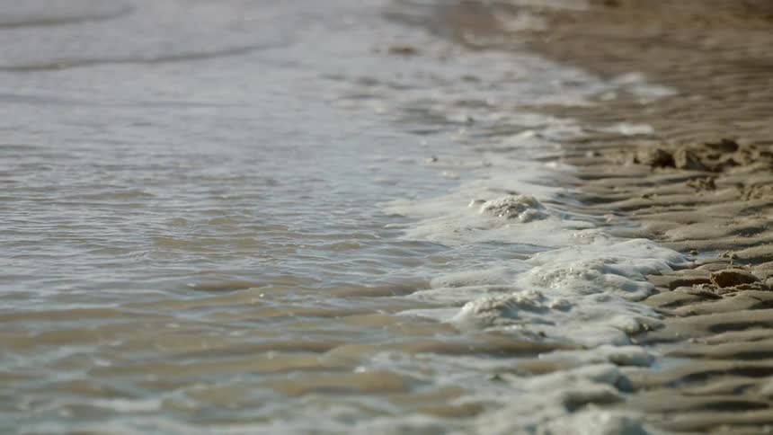 Foamy water washes ashore on a beach