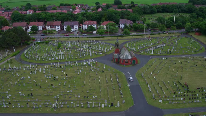 A vehicle drives through a cemetery in the countryside