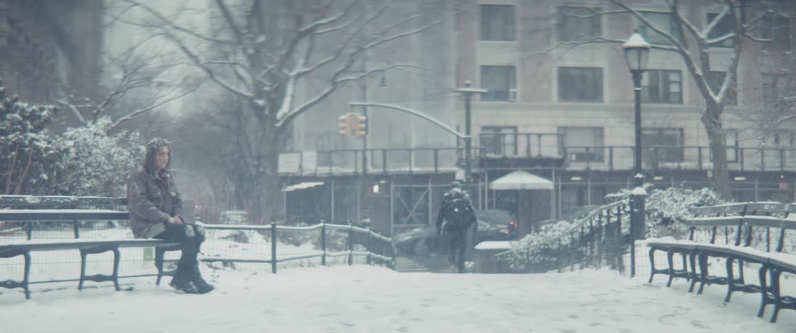 Woman sitting on a park bench during a snowy day