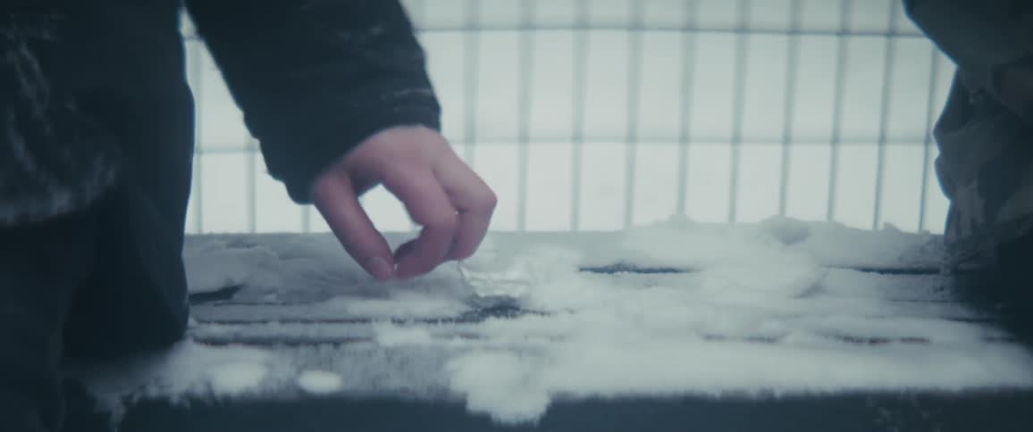 Close up of two people exchanging a product for money secretly while sitting on a bench outdoors during winter