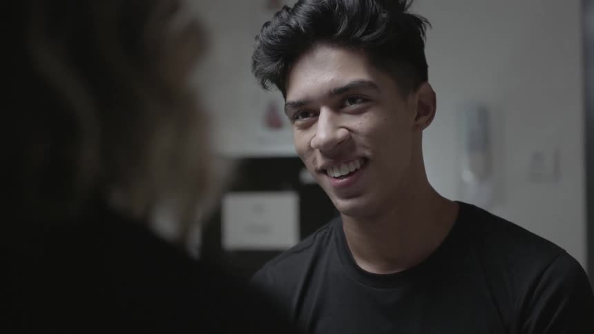 A man smiles while speaking with a woman