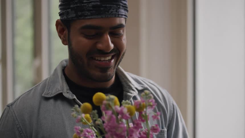 A man is smelling flowers and talking